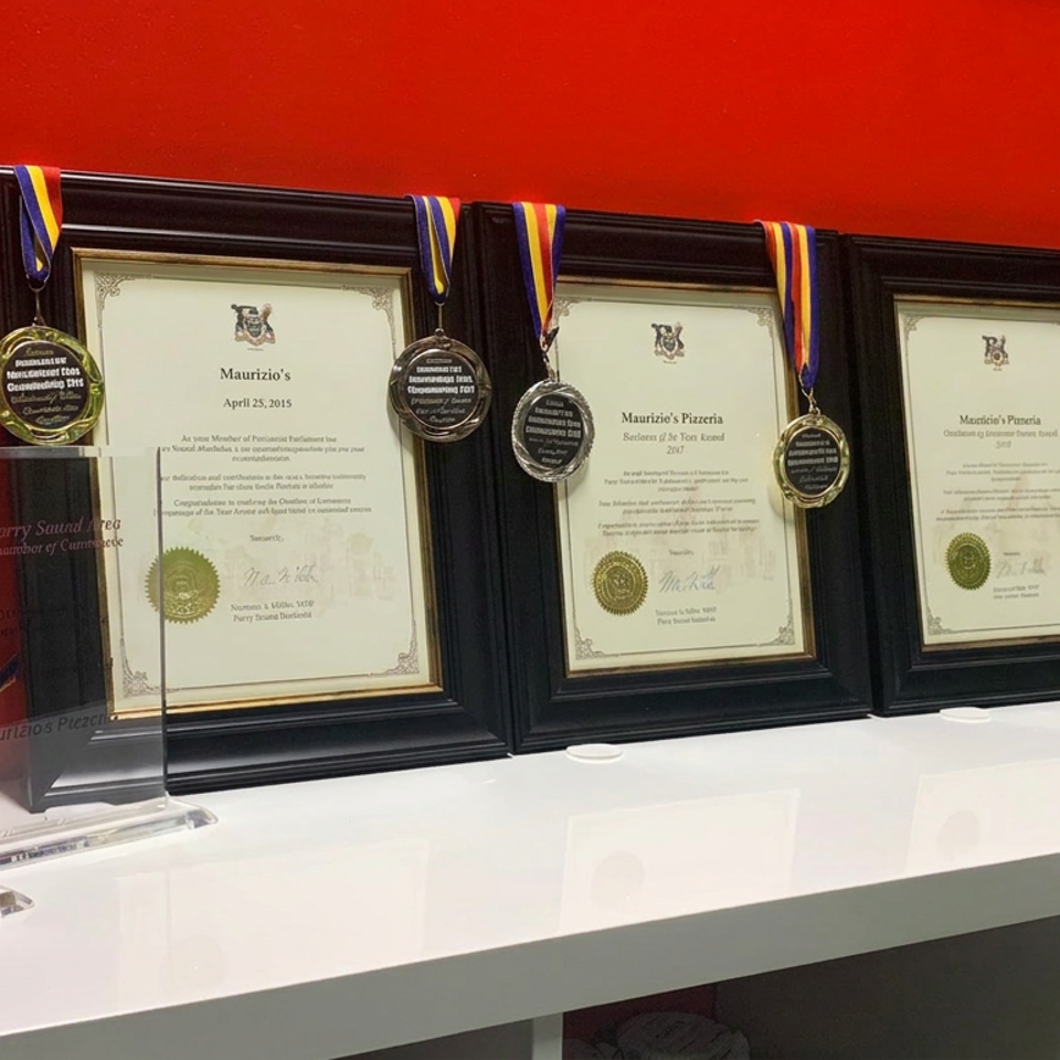 Awards, framed certificates, medals, and trophies displayed on a white shelf against a bright red wall.